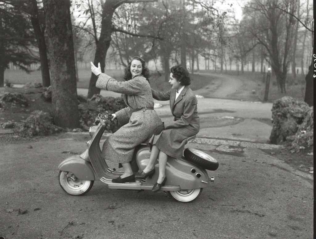 1950 two ladies on Lambretta scooter next to trees