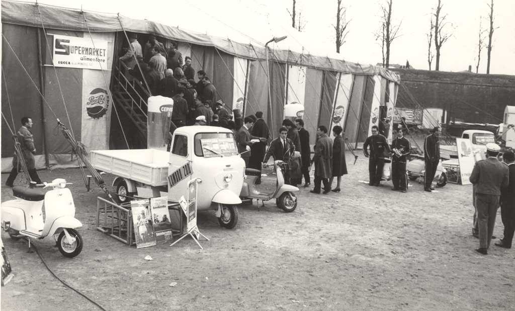 Three wheeler Lambro 200 in front of tent with people in a row
